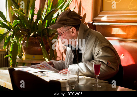 Old man reading newspaper in French bar - France. Stock Photo