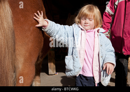 little girl touching a pony with her eyes closed Stock Photo