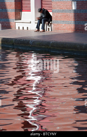 A man sits with head down near Birmingham' canal in the city centre. UK Stock Photo