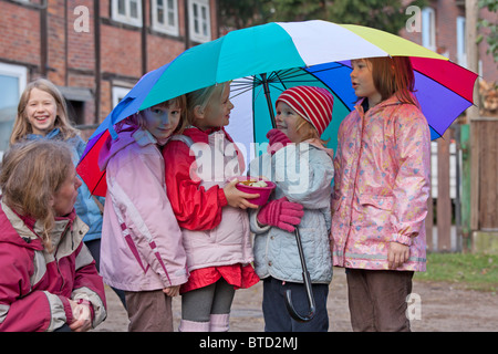 portrait of four small girls under a colourful umbrella Stock Photo