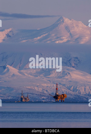 Three drill rigs in Cook Inlet with Mt. Spurr looming large in the background at sunset, Southcentral Alaska, Winter Stock Photo