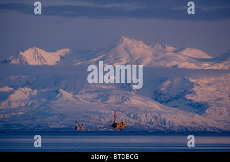 Three drill rigs in Cook Inlet with Mt. Spurr looming large in the background at sunset, Southcentral Alaska, Winter Stock Photo