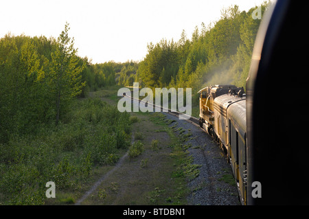 The Alaska Railroad's Coastal Classic train approaches Anchorage as it runs along Turnagain Arm in late evening, Alaska Stock Photo