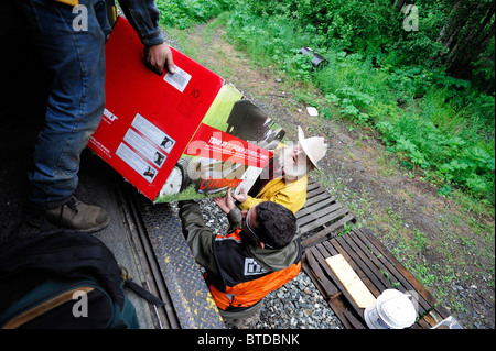 Alaska Railroad conductor helps a homestead passenger unload at his stop along the Hurricane Turn route, Alaska, Stock Photo