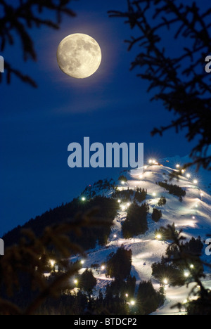 Winter moonrise over Mt. Alyeska during the annual Torchlight Parade, Girdwood, Southcentral Alaska, Winter, COMPOSITE Stock Photo