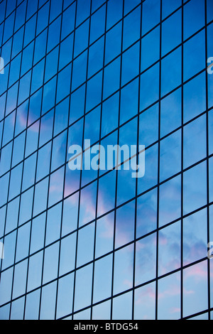 Clouds and sky reflected in windows on modern office building. Metallic ...