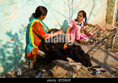 Jasbir Kaur and her mother sit in the late autumn sun talking as Jasbir sits down to late afternoon snack as mother sews. Stock Photo