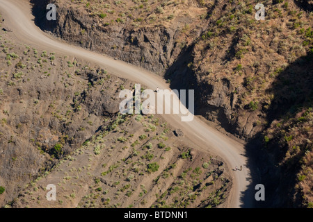 Locals walking with their livestock on a dirt road climbing steeply up the mountainside towards Lalibela Stock Photo