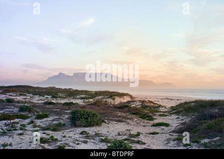 A view over coastal dunes at sunset towards Table Mountain in the distance