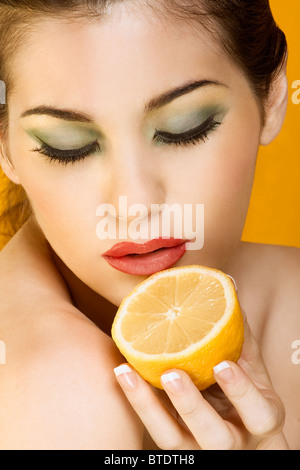 Gorgeous young woman wearing colorful make-up and holding half of lemon Stock Photo