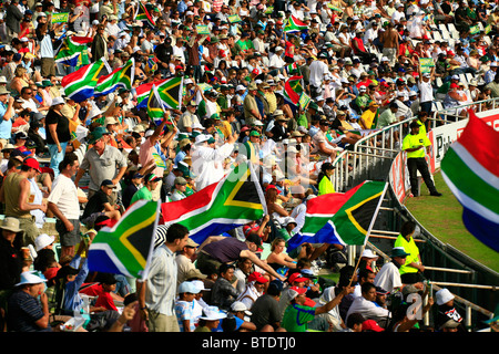 Large crowd of spectators cheering and waving South African flags before a cricket match in Cape Town Stock Photo