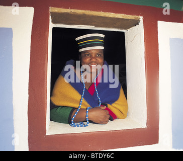 A portrait of a smiling Ndebele woman looking out of a window. Stock Photo