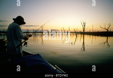 Fisherman fishing from a boat on Lake Kariba at sunset Stock Photo