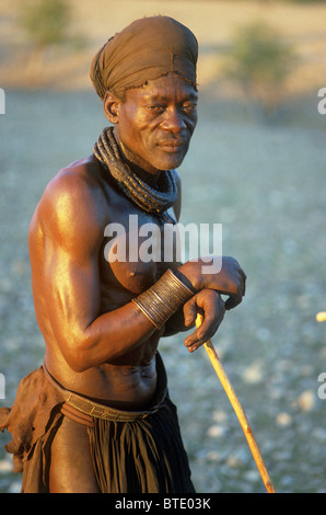 Himba man dressed in traditional dress leaning on a walking stick Stock Photo