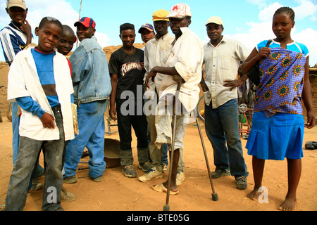 Group of people at the roadside in southern Angola, including one man with crutches who had a leg blown off by a land mine Stock Photo