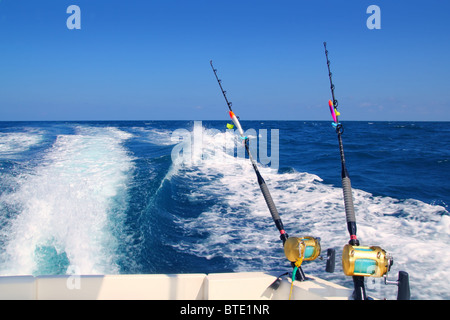 Trolling fishing boat rod and golden saltwater reels deep blue ocean sea wake Stock Photo