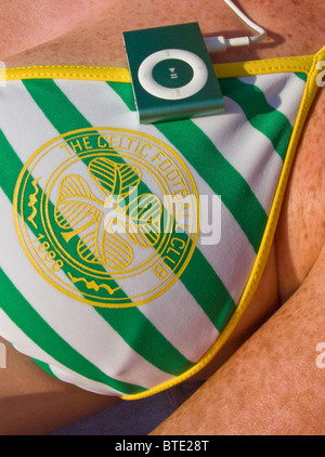 SELECTIVE FOCUS DETAILED IMAGE OF A WOMAN WEARING A CELTIC FOOTBALL CLUB BIKINI AND LISTENING TO IPOD Stock Photo