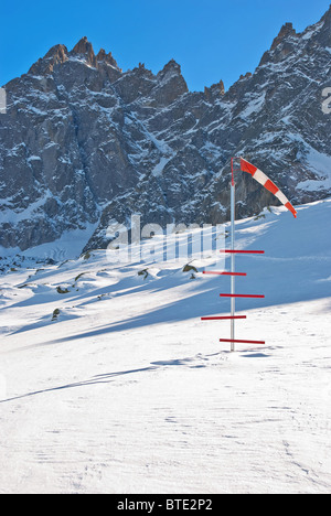 Windsock and snow level meter at helicopter landing area high in snowy mountains. French Alps. Chamonix. Stock Photo