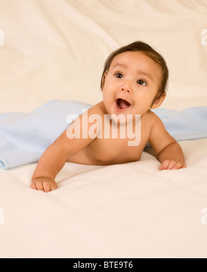 Surprised infant lying down on his tummy on blanket with open mouth Stock Photo