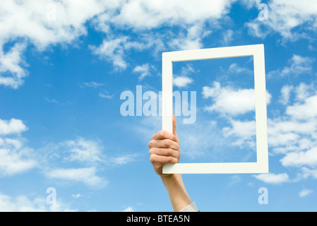 Person holding picture frame in front of sky Stock Photo
