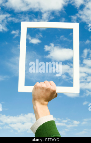Person holding picture frame in front of sky Stock Photo