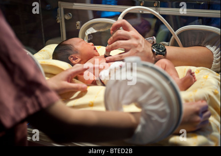 Newborn baby in incubator being examined by doctor and nurse, close up Stock Photo