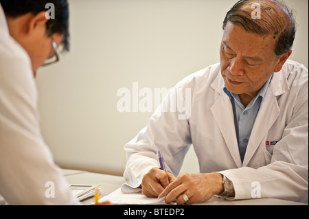 Doctors working and writing charts at desk in hospital Stock Photo