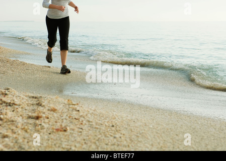 Woman jogging at the beach, low section Stock Photo