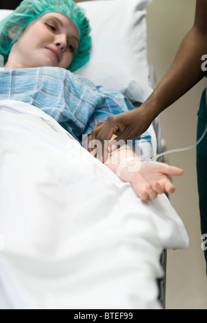 Patient watching as nurse checks IV needle placement in arm Stock Photo