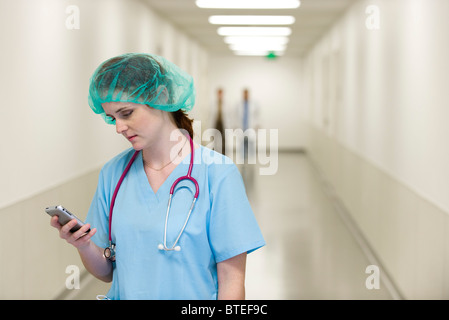 Nurse in hospital corridor using cell phone Stock Photo