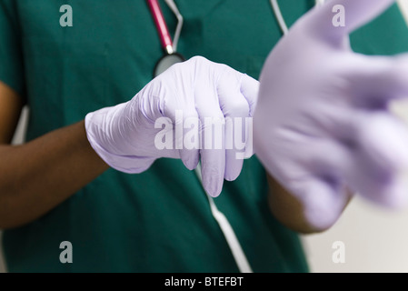Healthcare worker putting on latex gloves Stock Photo