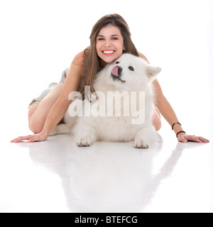 a studio image of a young woman and her white dog, with her sitting on her hands and knees on top of the dog, looking forward, s Stock Photo