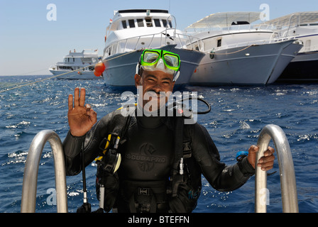 Scuba diver climbing a ladder on a diving boat in the Red Sea Stock Photo