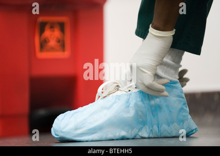 Healthcare worker putting on disposable shoe covers Stock Photo
