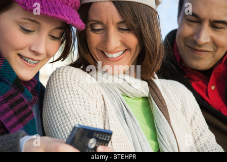 Teenage daughter showing cell phone to her parents Stock Photo