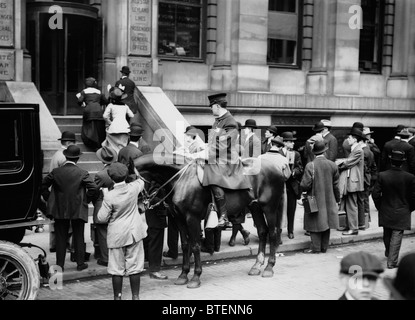 A policeman patrols outside the White Star Line offices in New York as crowds gather following the Titanic disaster in 1912. Stock Photo