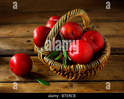 Fresh picked whole uncooked red Victoria plums in a basket Stock Photo