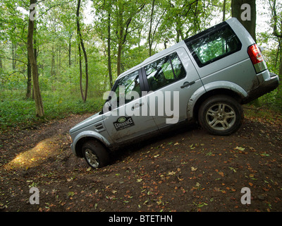 Silver Land Rover Discovery 4 driving through a forest at the Domaine d'Arthey estate in Belgium Stock Photo