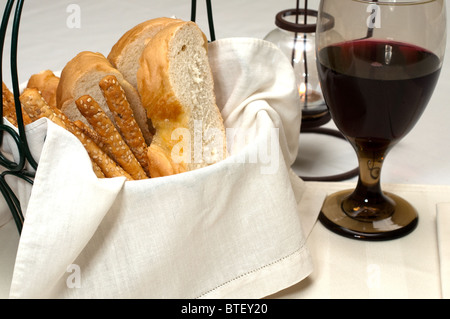 Italian bread and bread sticks in basket with red wine and candle. Stock Photo