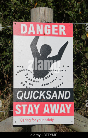 A 'Quicksand' warning sign at the edge of a lake in England, UK. Stock Photo