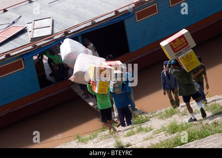 Chinese laborers are loading a cargo boat with boxes of goods on the Mekong River in Chiang Sean, Thailand. Stock Photo