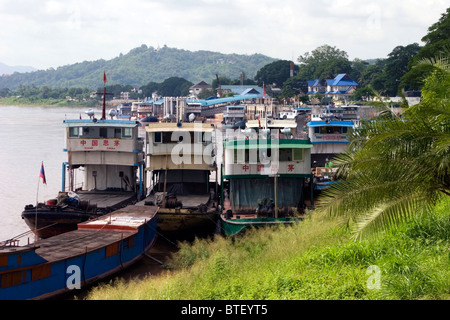 Chinese cargo boats from China used to import and export goods are docked on the Mekong River in Chiang Sean, Thailand. Stock Photo