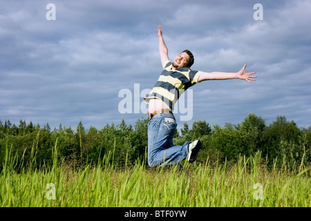 The young man joyfully jumps up in a grass Stock Photo