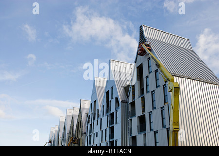 Construction workers using cherry picker crane to work on building exterior Stock Photo