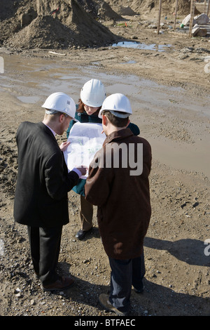 Architect meeting with engineers at construction site discussing blueprints Stock Photo