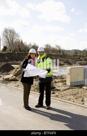 Architect and building contractor discussing blueprint at construction site Stock Photo