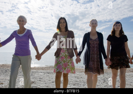 Group of people holding hands, walking on beach Stock Photo