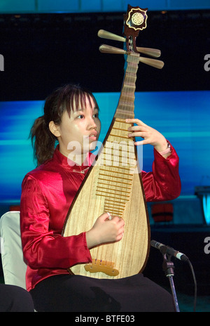 Young woman playing four stringed ancient Chinese lute family classical musical instrument known as a pipa. Hong Kong, China Stock Photo