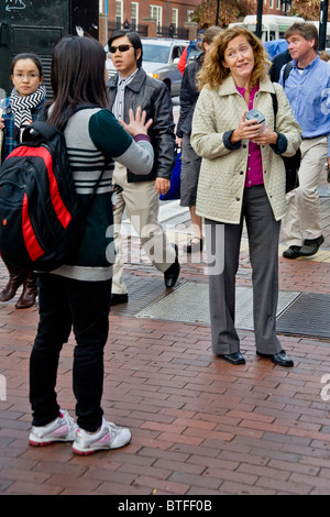 Two women have a spirited conversation on Massachusetts Avenue in Harvard Square, Cambridge, MA. Note Asian students. Stock Photo