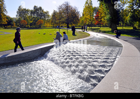 People at Princess Diana memorial fountain Hyde Park forms a circular artificial rill water feature with Autumn colours on trees London England UK Stock Photo